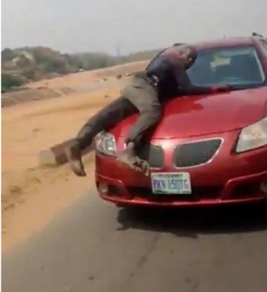 Police officers on top car bonnet